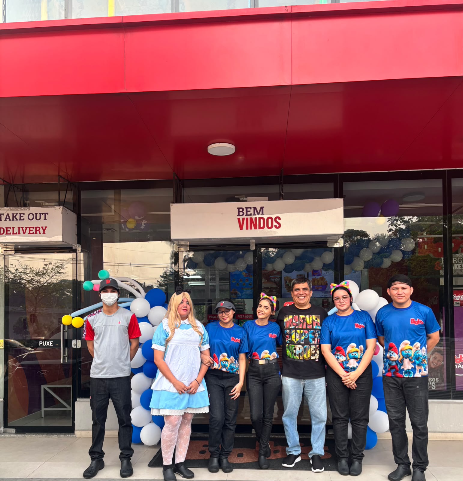 Equipe de uma loja Bob’s com fantasias e camisas temáticas na entrada da loja no Dia das Crianças